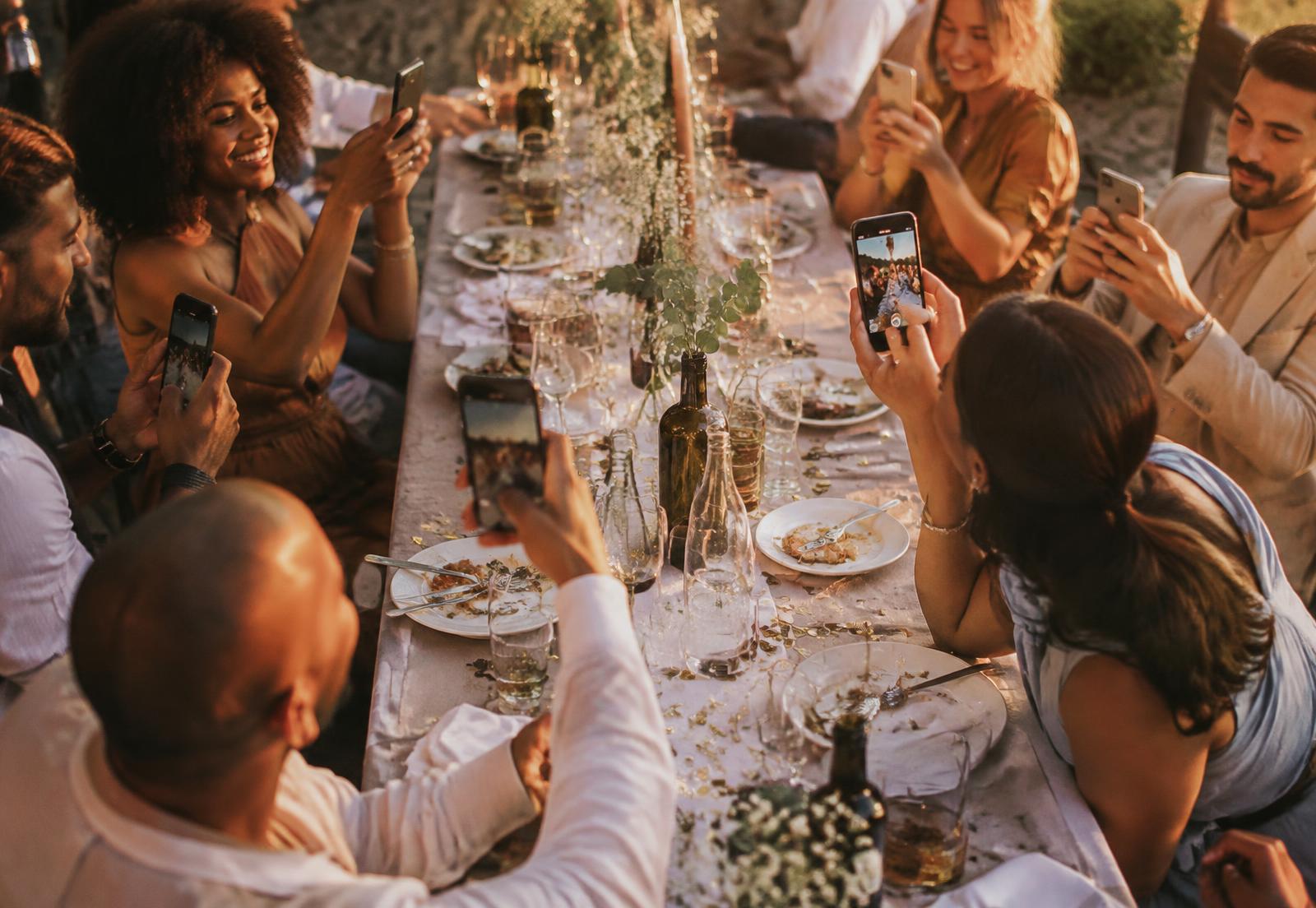 Guests photographing a dinner celebration on their phones